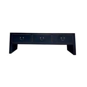 May include: A black wooden console table with three drawers and decorative metal handles. The table has a simple, elegant design and is perfect for a living room or entryway.