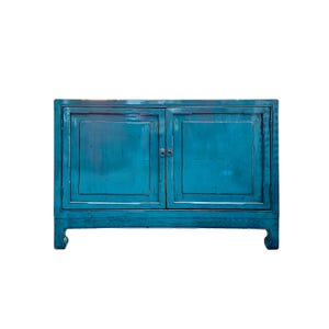 May include: A teal blue wooden cabinet with two doors and simple metal handles. The cabinet has a traditional style with a slightly distressed finish.
