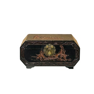 May include: A black wooden box with intricate carvings of a landscape scene. The box has a brass latch and a raised octagonal design around the edges.