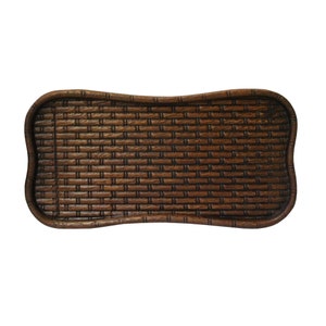 Peut inclure: Un plateau rectangulaire tissé brun avec un bord incurvé et festonné. Le plateau présente un motif de tissage en osier et est fait d'un matériau brun foncé. Le plateau est vide et repose sur un fond blanc.