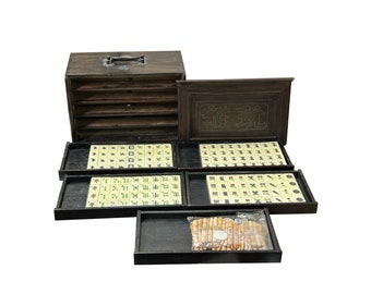 Puede incluir: Un juego de mahjong de madera vintage con una caja de madera tallada, fichas y un juego de dados. Las fichas están dispuestas en una cuadrícula y presentan caracteres chinos tradicionales.