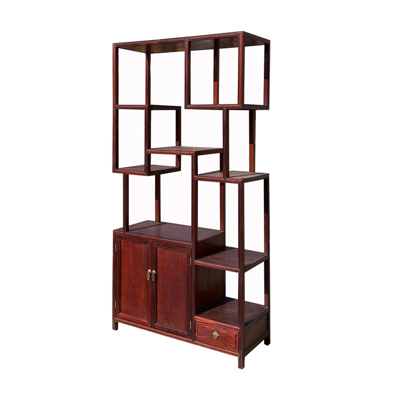 May include: A dark brown wooden shelf unit with a geometric design. The shelf has two doors, a drawer, and multiple open shelves.