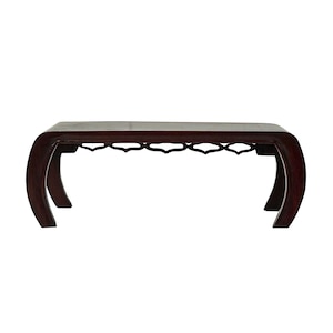 May include: A dark brown wooden coffee table with a curved design and an intricate cutout pattern on the bottom shelf.