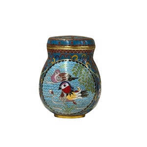 May include: A decorative, antique cloisonné jar with a lid. The jar features a blue background with a design of two birds, water, and foliage. The jar has gold accents and a detailed pattern.