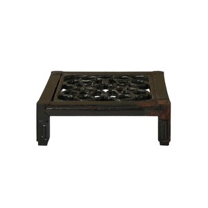 Puede incluir: Un soporte de madera negro con una parte superior decorativa calada. El soporte tiene una base cuadrada y cuatro patas.