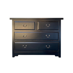 May include: A black wooden dresser with five drawers and silver handles. The dresser has a distressed finish and a simple design.