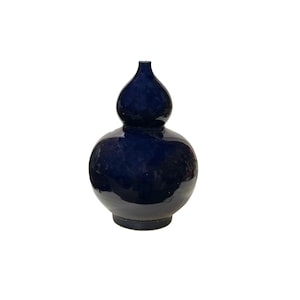 May include: A dark blue ceramic vase with a gourd shape. The vase has a wide base and a narrow neck.