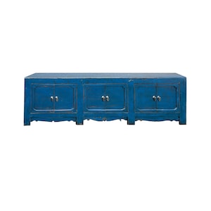 May include: A long, rectangular blue wooden sideboard featuring three sets of double doors. Each pair of doors is equipped with small, metallic silver-toned hardware pulls. The furniture piece has a distressed finish and a low-profile base.