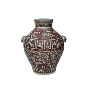 May include: A large, white ceramic vase with a red glaze and intricate white designs. The vase has two handles shaped like animal heads and features a phoenix, flowers, and geometric patterns.