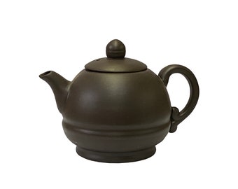 May include: A dark brown ceramic teapot with a rounded body and a small knob on the lid. The teapot has a handle on the side and a spout on the front.