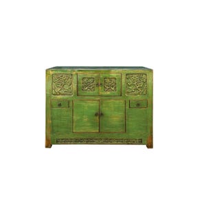 May include: A green antique cabinet with carved floral details and two drawers on each side. The cabinet has two doors with brass handles and a decorative trim around the bottom.