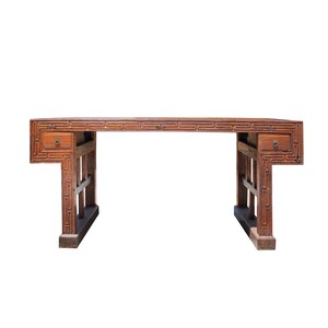May include: A wooden desk with a rectangular top and two drawers. The desk is made of dark brown wood and features intricate geometric patterns. The desk has a classic design and is suitable for a home office or study.