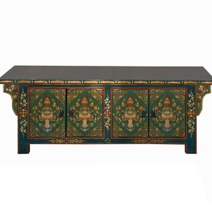 May include: A dark green wooden cabinet with three doors and intricate floral designs painted in gold, red, and blue. The cabinet has a flat top and sits on four legs.