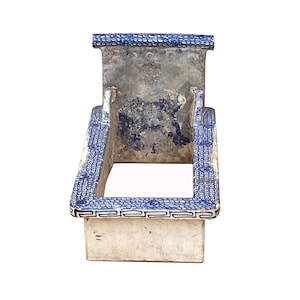 May include: A white ceramic planter with a blue and white geometric pattern. The planter has a rectangular shape with a raised back and a square opening.