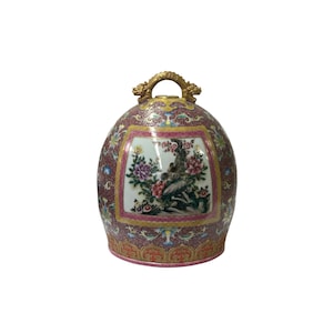 May include: A pink and gold porcelain egg-shaped container with a floral design and a gold handle. The container has a square panel with a floral design and a bird.