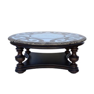 May include: A round, dark brown wooden coffee table with a marble top featuring a white and brown geometric design. The table has a lower shelf and four turned legs.