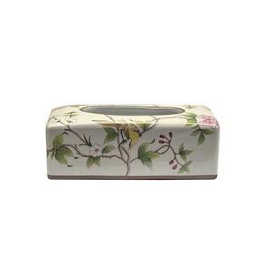 Könnte beinhalten: Ein weißer Keramik-Tischtuchhalter mit einem Blumendesign mit rosa Blüten, grünen Blättern und einem gelben Vogel.