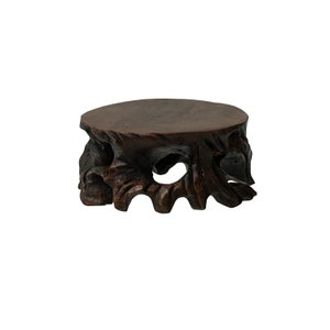 May include: A dark brown wooden pedestal with a round top and a carved, intricate base.