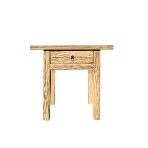 May include: A wooden end table with a single drawer and a simple design. The table has a light brown finish and is made of reclaimed wood.