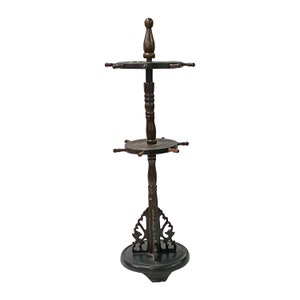 May include: A dark brown wooden stand with two circular shelves and a decorative base. The stand has a ship's wheel design with spokes extending from the shelves.