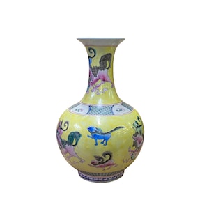 Peut inclure: Un vase en céramique jaune avec une base large et un col étroit. Le vase est décoré d'un motif floral coloré et de créatures mythologiques.