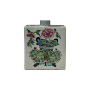 Könnte beinhalten: Ein quadratischer Keramikbehälter mit hellgrauer Oberseite und floralem Design. Der Behälter zeigt ein rosa-grünes Blumenmotiv mit einem blau-grünen Vasendesign. Der Behälter ist mit einem rosa-grünen Blumenmuster verziert.