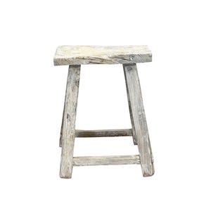 May include: A weathered white wooden stool with a simple design. The stool has a rectangular seat and four legs.