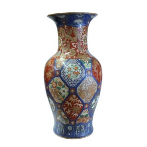 May include: A large, blue and red ceramic vase with a geometric pattern of flowers and leaves. The vase has a wide mouth and a narrow neck.