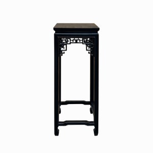 May include: Black wooden side table with intricate carved details and a square top. The table has a traditional Chinese design.