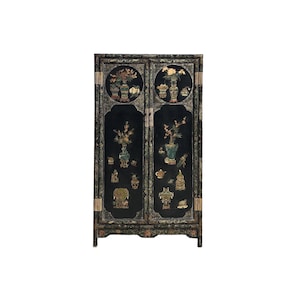 May include: Black cabinet with ornate floral and decorative designs. The cabinet features two doors with detailed artwork of vases, flowers, and other objects. Gold accents and hardware add to the cabinet's aesthetic appeal.
