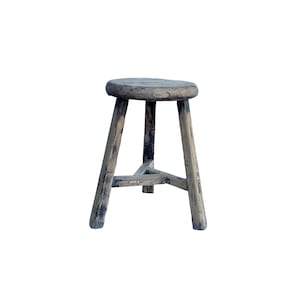 May include: A rustic wooden stool with a round seat and three legs. The stool is made of weathered wood with a dark brown finish.