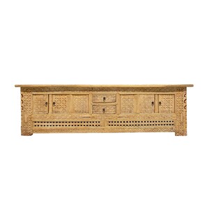 May include: A long, light-colored wooden cabinet with intricate carved designs. The cabinet features two sets of doors, two drawers, and a decorative lattice pattern along the bottom. The wood has a natural finish, showcasing the grain and texture.