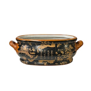 May include: An oval-shaped black ceramic planter with gold painted details and Chinese characters. The planter has two handles and a brown rim.