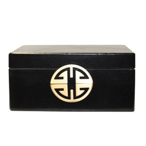 Puede incluir: Caja de madera negra con un símbolo chino de metal dorado en la tapa.