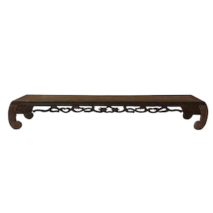 May include: A dark brown wooden table with intricate carvings on the underside of the tabletop and the legs. The table has a rectangular top and curved legs.