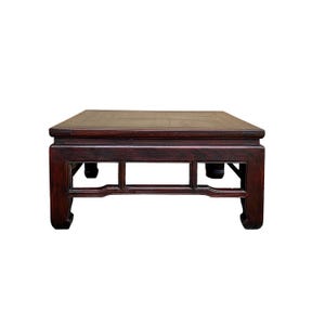 May include: A dark reddish-brown, square, low table with a rectangular top and decorative apron. The table has four legs with curved feet and a simple, open design. The wood grain is visible, giving it a classic, antique look.
