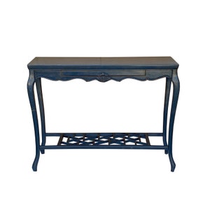May include: A dark blue console table with a single drawer and a lower shelf. The table has ornate legs and a carved design on the front edge.