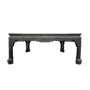 May include: A dark, rectangular wooden table featuring intricate, deep relief carvings of dragons along the apron and legs. The table stands on four sturdy, carved feet, with a flat top surface and detailed ornamentation across the entire frame.