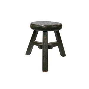 May include: A small, dark green wooden stool with a round seat and three legs. The stool has a distressed finish, with visible wear and tear on the paint. The legs are angled outwards for stability.
