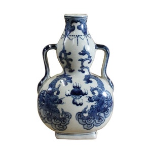 Puede incluir: Un jarrón de cerámica blanca con diseños florales y de dragones azules y blancos. El jarrón tiene dos asas y una forma de calabaza.