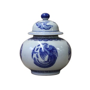 Puede incluir: Un jarrón de porcelana blanca con un diseño de fénix azul y blanco. El jarrón tiene una tapa con un diseño de nube azul y blanco.