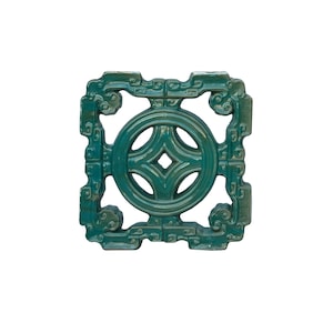 May include: A square green ceramic tile with an intricate design. The tile features a circular pattern with a diamond in the centre, surrounded by a decorative border.