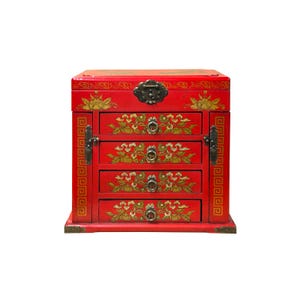 Puede incluir: Un joyero de madera rojo con cuatro cajones, adornado con diseños florales dorados y herrajes de latón. La caja tiene forma rectangular con tapa abisagrada y detalles decorativos en las esquinas. El diseño es ornamentado y tradicional.