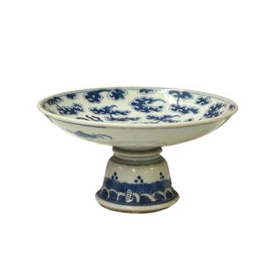 May include: A white ceramic pedestal bowl with a blue and white floral design. The bowl is on a stand with a similar design.