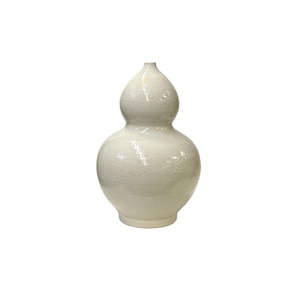 May include: A white ceramic vase with a textured finish. The vase has a double gourd shape.