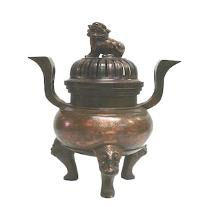 Peut inclure: Un brûle-encens en bronze avec un lion sur le couvercle. Le brûleur a trois pieds et des détails complexes sur le corps.