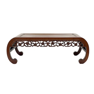 May include: A low, rectangular wooden table with a dark brown finish. The table features curved legs with scroll details and a decorative floral pattern along the apron. The table is approximately 30 inches long.