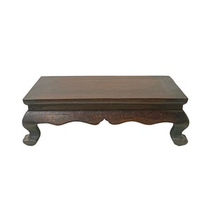 May include: A dark brown wooden table with a rectangular top and four legs. The legs are curved and have a decorative design.