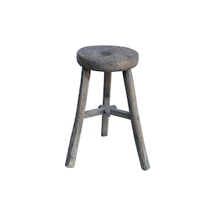 May include: A rustic wooden stool with a round seat and three legs. The stool is made of weathered wood and has a natural finish.