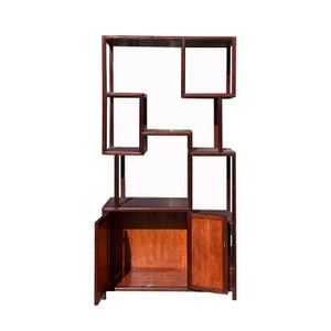 May include: A dark wood bookshelf with a unique geometric design. It has multiple shelves and two doors that open to reveal storage space.